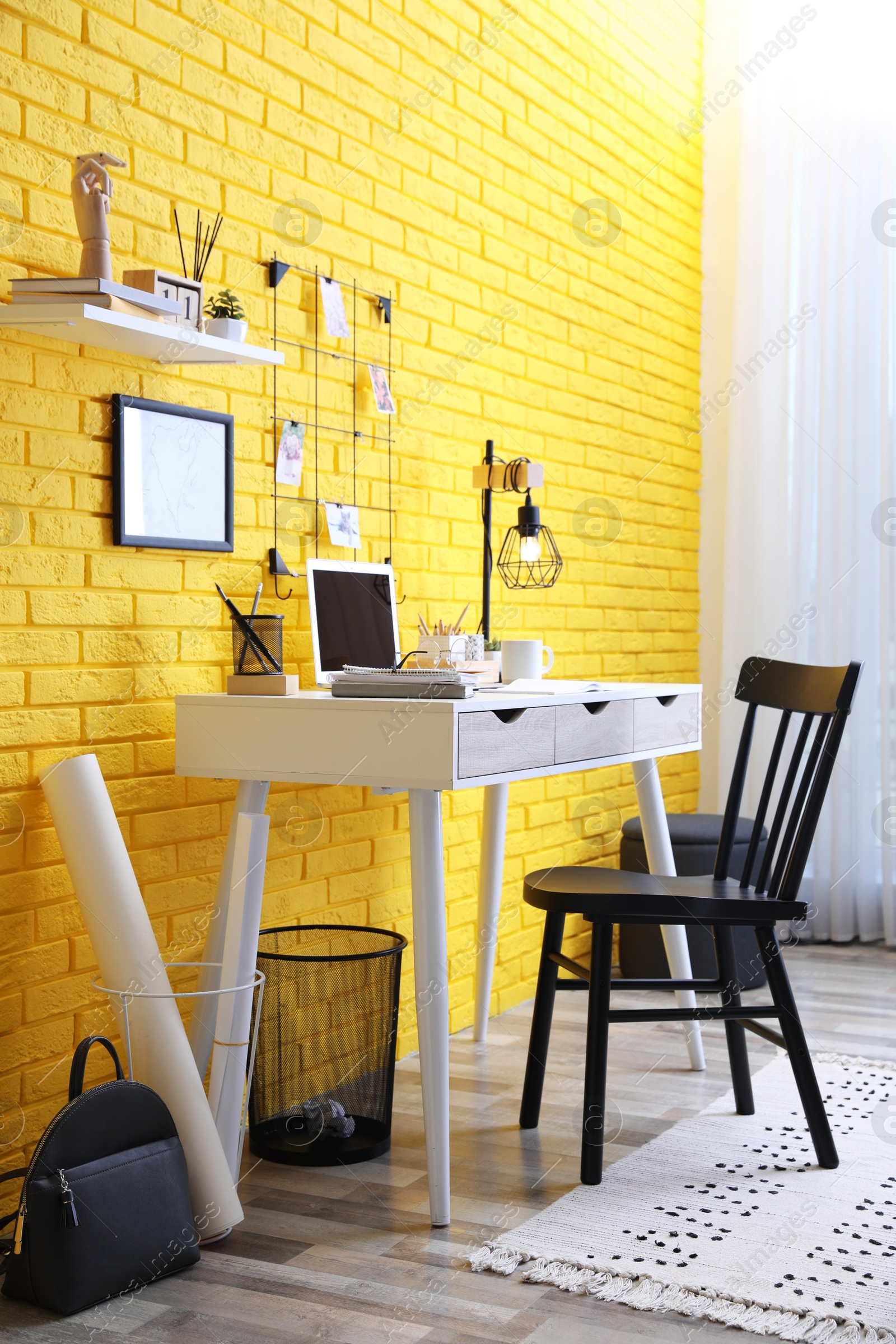 Photo of Stylish home office interior with comfortable workplace near yellow brick wall