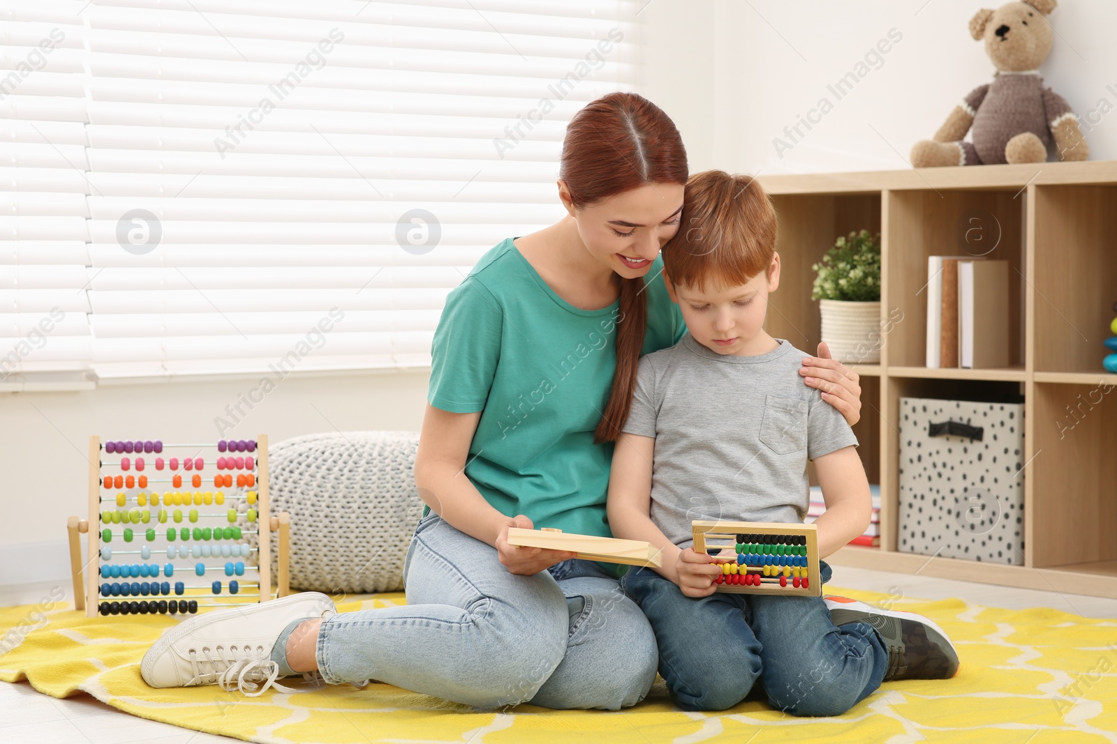 Photo of Happy mother and son playing with different math game kits on floor in room. Study mathematics with pleasure