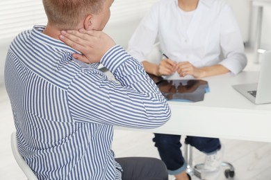 Doctor consulting patient at table in clinic, closeup. Neck MRI