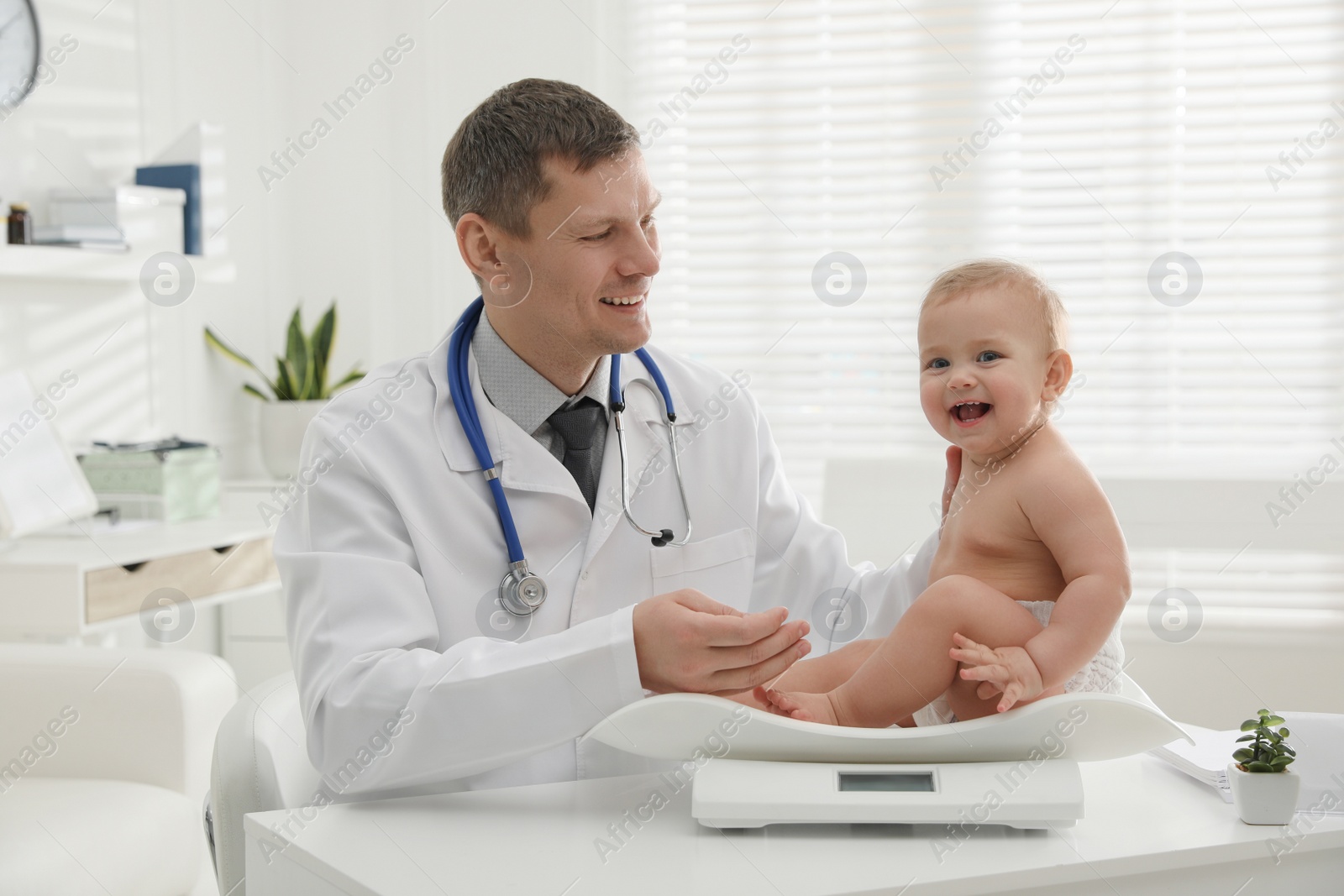 Photo of Pediatrician weighting cute little baby in clinic