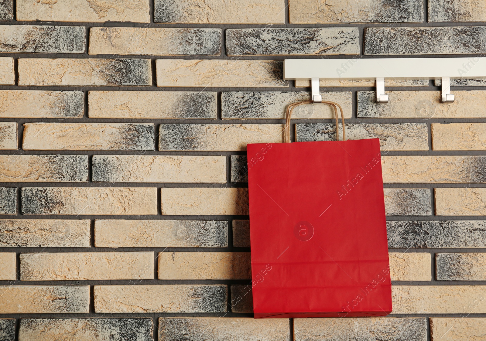 Photo of Rack with paper shopping bag on brick wall