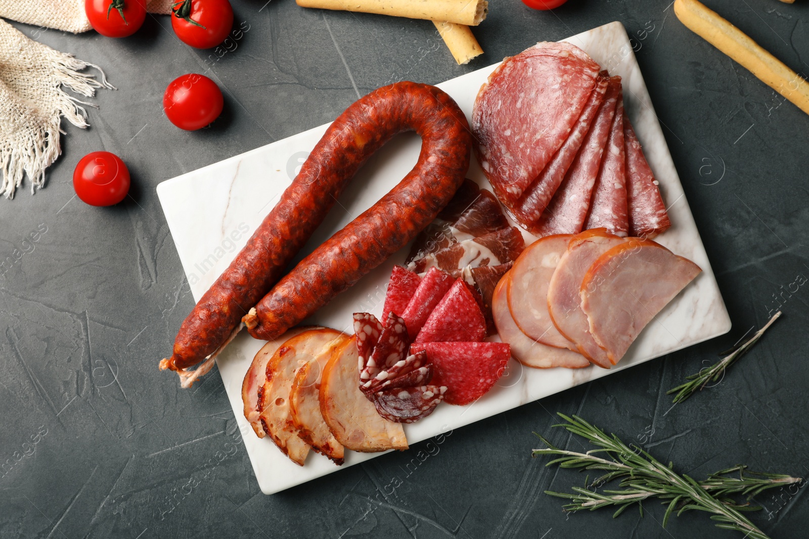 Photo of Cutting board with different sliced meat products on table, flat lay. Space for text