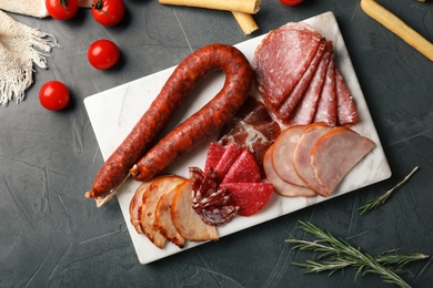 Cutting board with different sliced meat products on table, flat lay. Space for text