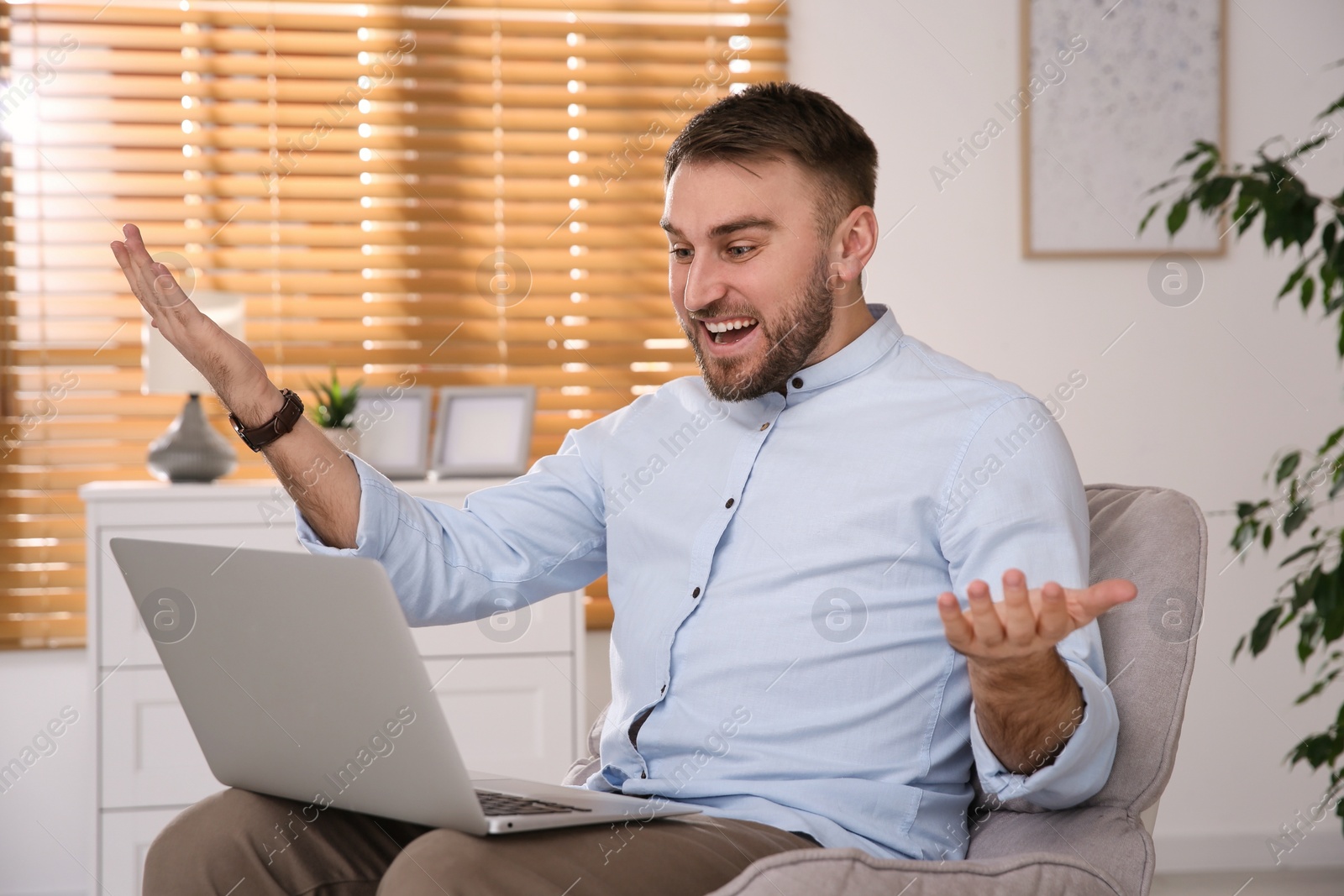 Photo of Emotional man participating in online auction using laptop at home