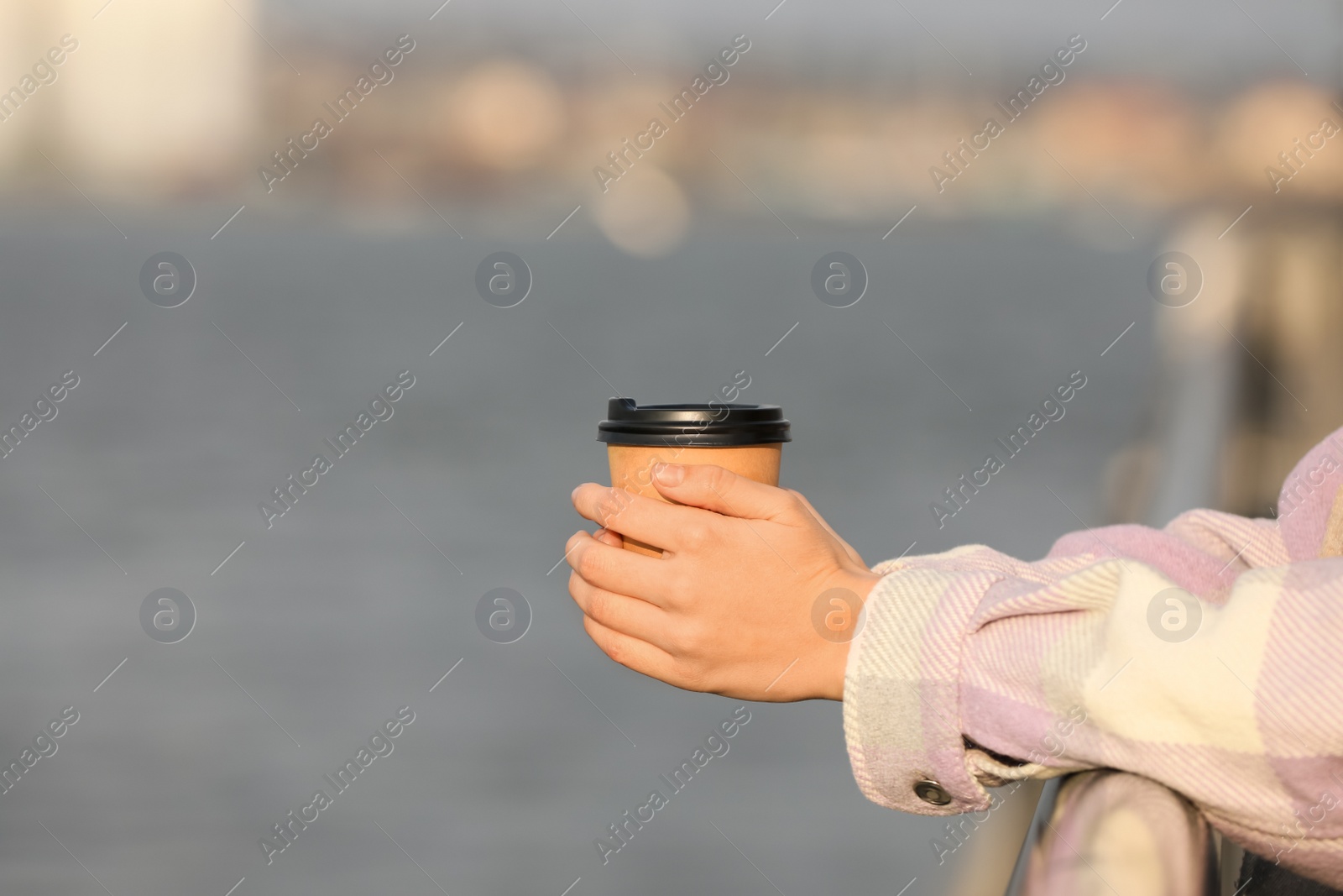 Photo of Woman holding paper coffee cup outdoors, closeup. Space for text