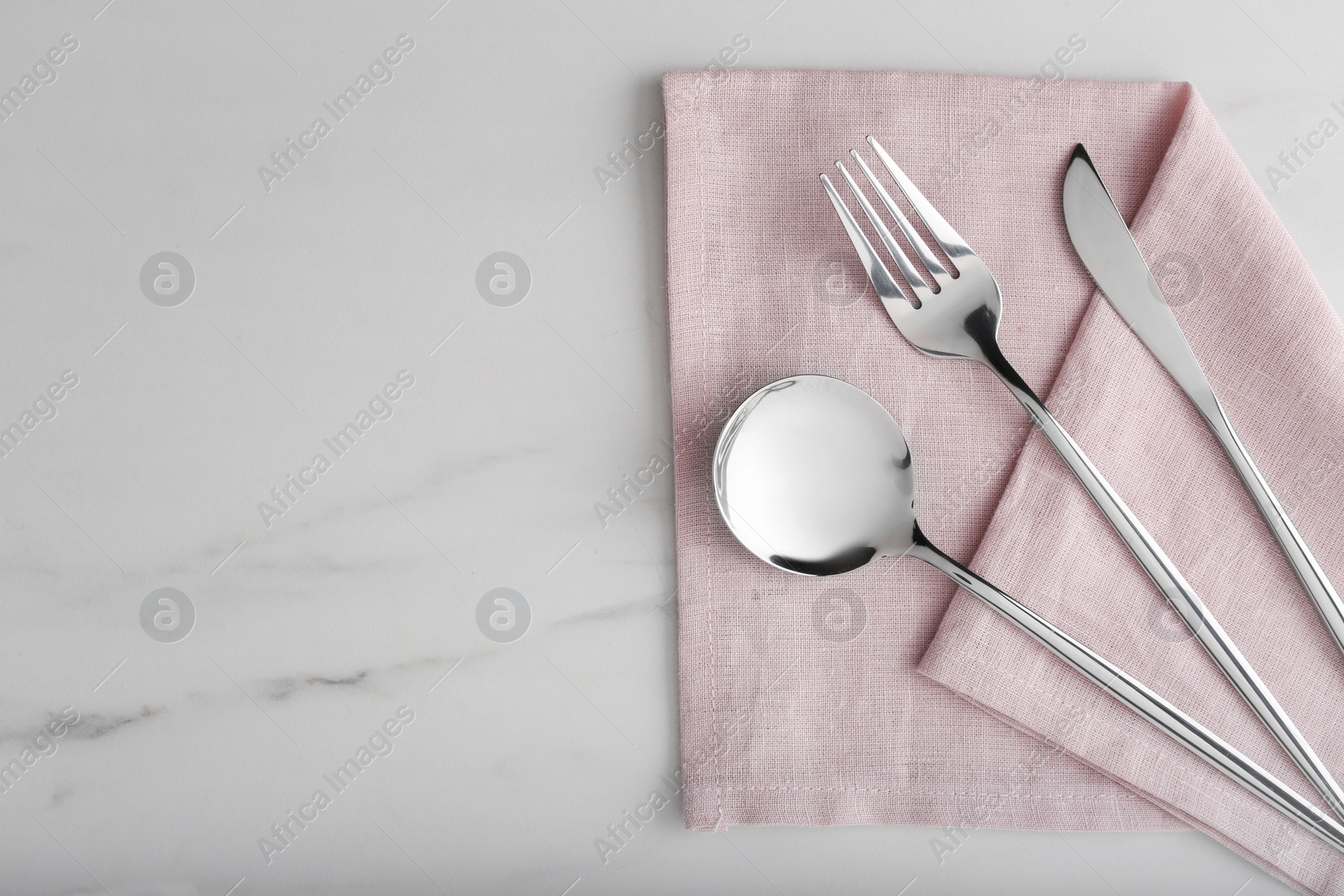 Photo of Stylish cutlery set and napkin on white marble table, flat lay. Space for text