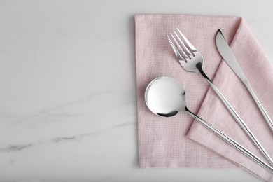 Photo of Stylish cutlery set and napkin on white marble table, flat lay. Space for text