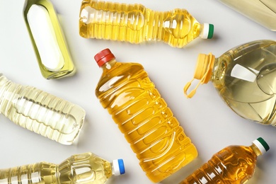 Photo of Bottles of oils on light background, top view