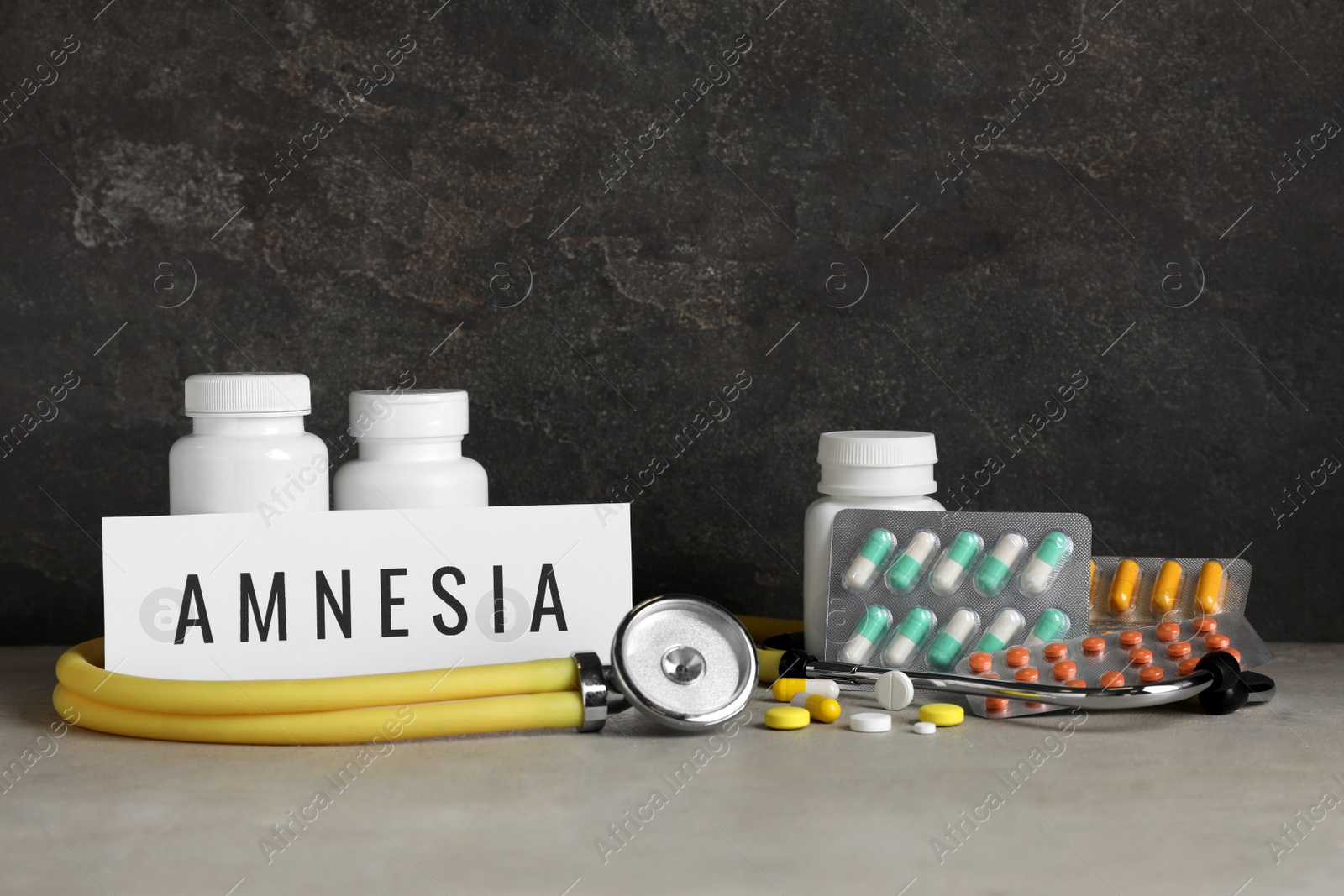 Photo of Card with word Amnesia, drugs and stethoscope on light grey table