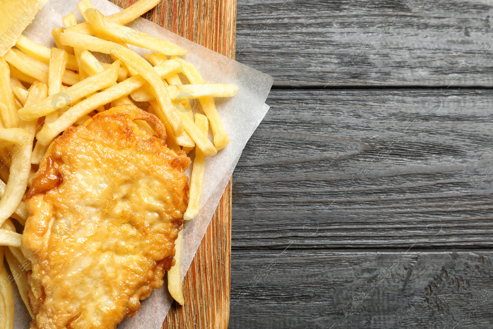 Photo of Board with British traditional fish and potato chips on wooden background, top view. Space for text