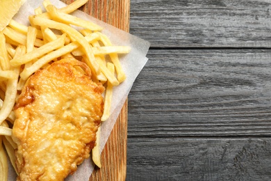 Photo of Board with British traditional fish and potato chips on wooden background, top view. Space for text