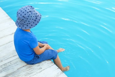 Photo of Little child near outdoor swimming pool. Dangerous situation