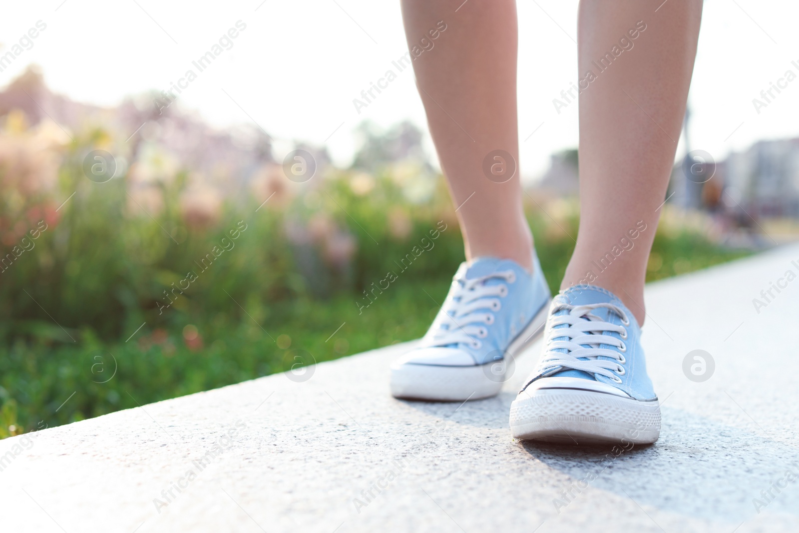 Photo of Woman in stylish sneakers walking outdoors, closeup. Urban fashion