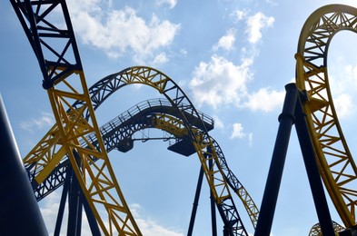 Amusement park. Beautiful large rollercoaster against blue sky, low angle view