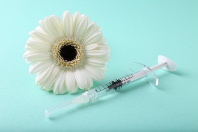 Cosmetology. Medical syringe and gerbera flower on turquoise background