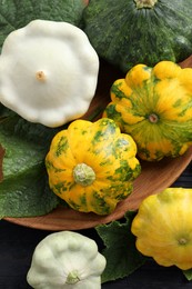 Photo of Fresh ripe pattypan squashes with leaves on black  table, flat lay