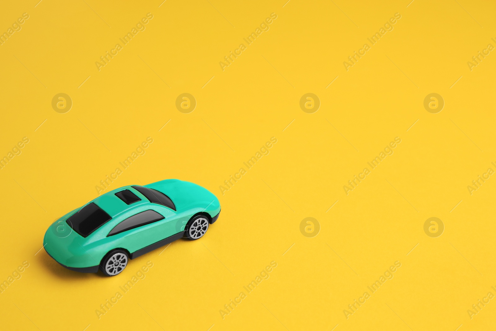Photo of One turquoise car on yellow background, space for text. Children`s toy