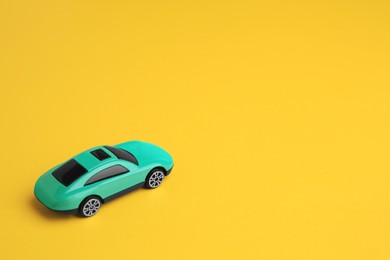 Photo of One turquoise car on yellow background, space for text. Children`s toy