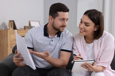 Young couple with papers discussing pension plan indoors