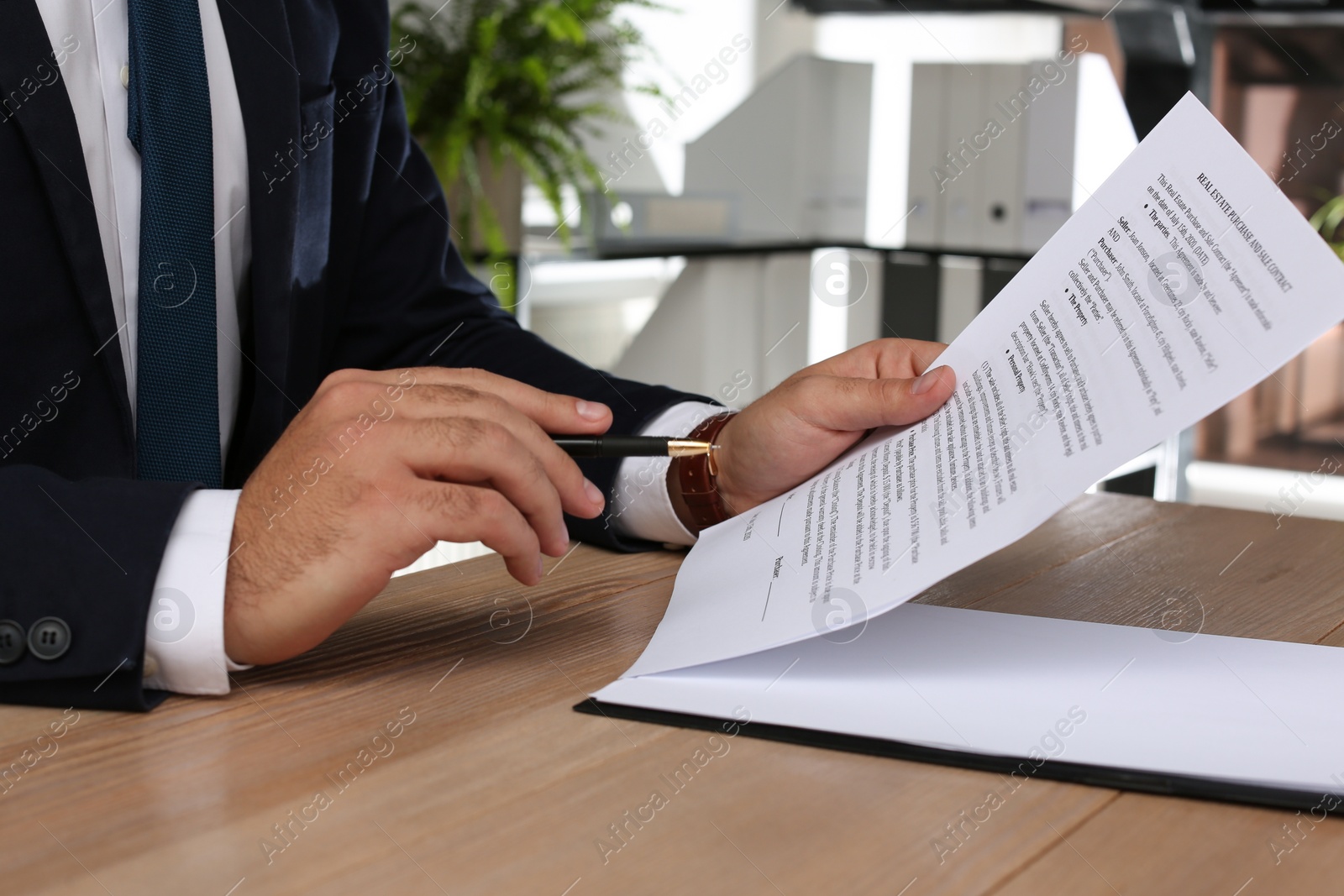 Photo of Man signing Real Estate Purchase And Sale Contract at wooden table indoors, closeup