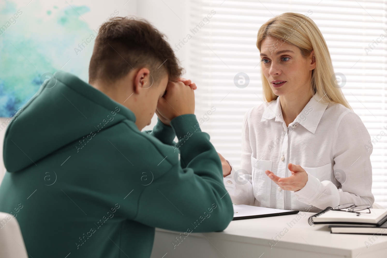 Photo of Psychologist working with teenage boy at table in office