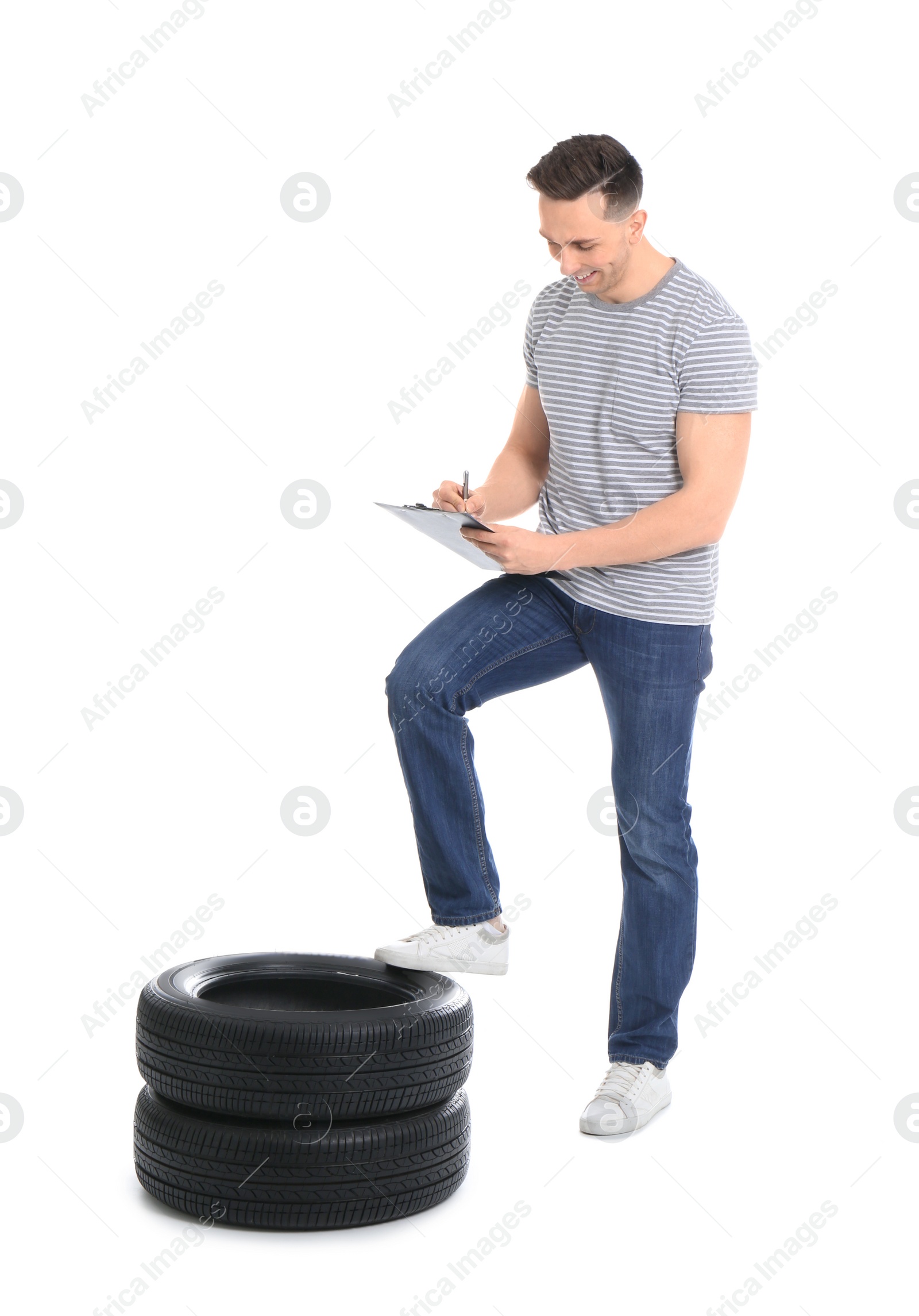 Photo of Young man with car tires and clipboard on white background