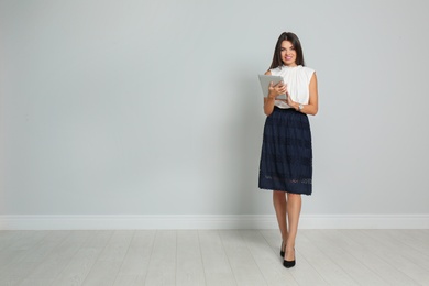 Photo of Beautiful woman with tablet wearing office clothes against gray wall. Space for text
