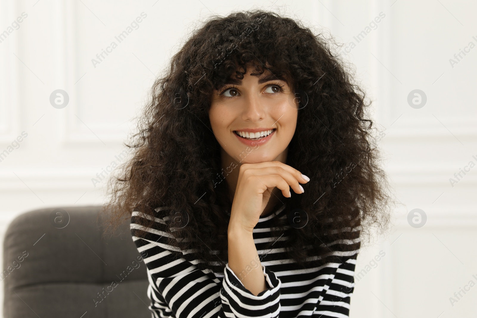 Photo of Portrait of beautiful woman with curly hair indoors. Attractive lady posing for camera