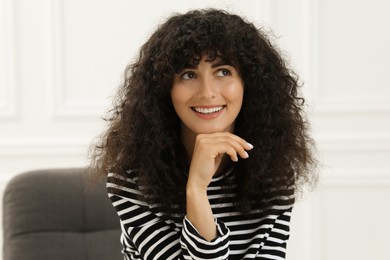 Photo of Portrait of beautiful woman with curly hair indoors. Attractive lady posing for camera