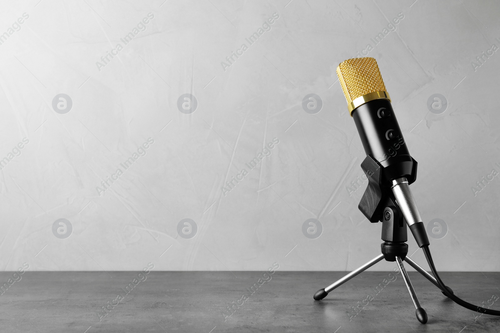 Photo of Microphone on table against grey background. Space for text