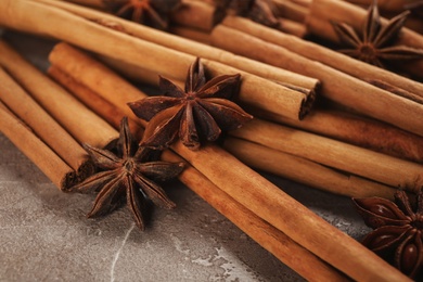 Photo of Aromatic cinnamon sticks and anise on grey marble table, closeup