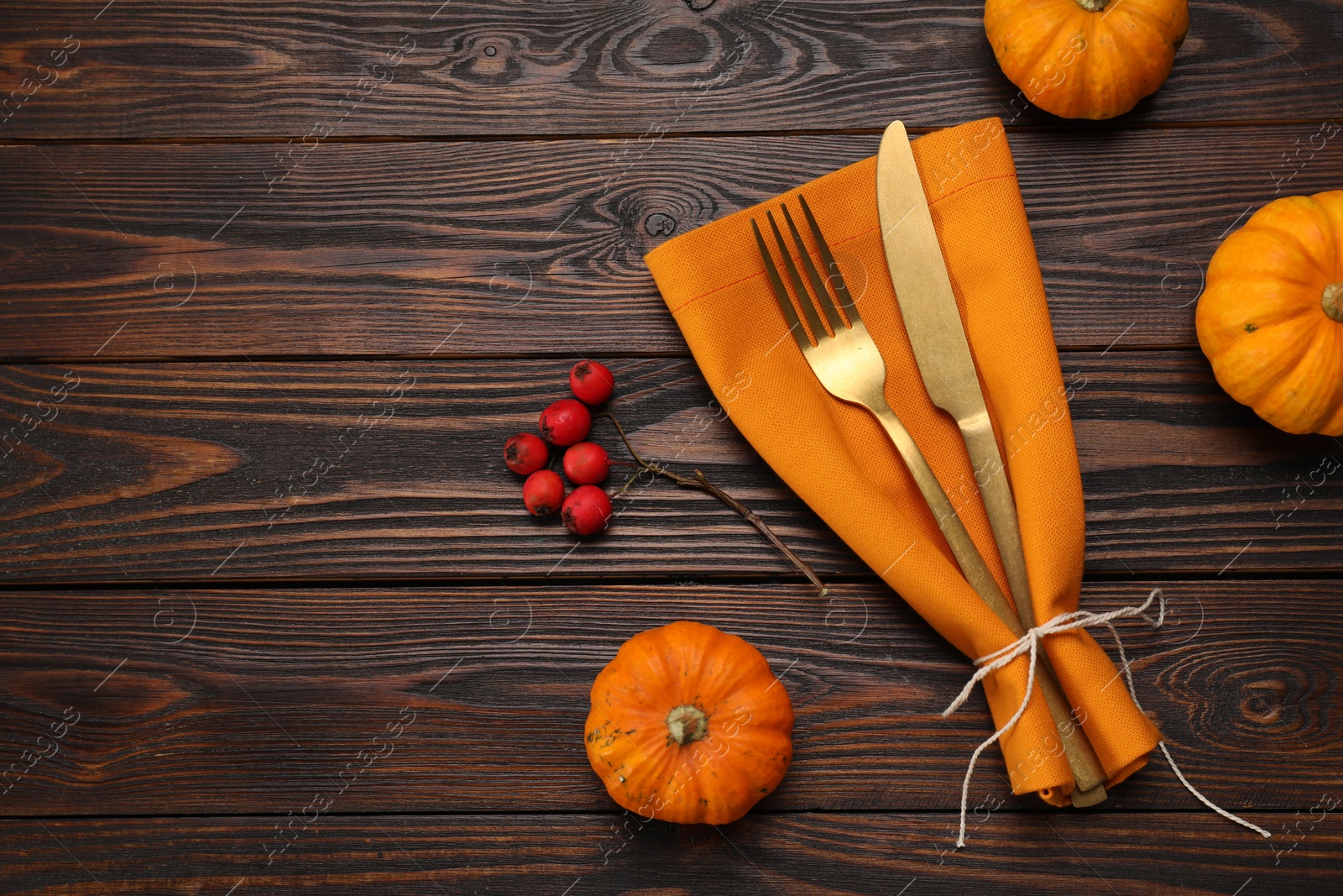 Photo of Cutlery, napkin and pumpkins on wooden background, flat lay with space for text. Table setting