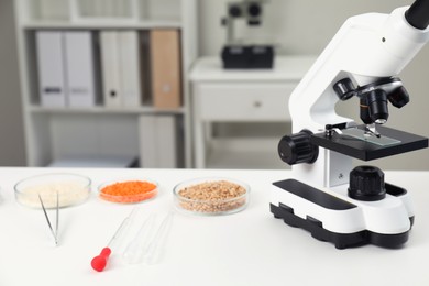 Food quality control. Microscope, petri dishes with different products and other laboratory equipment on white table