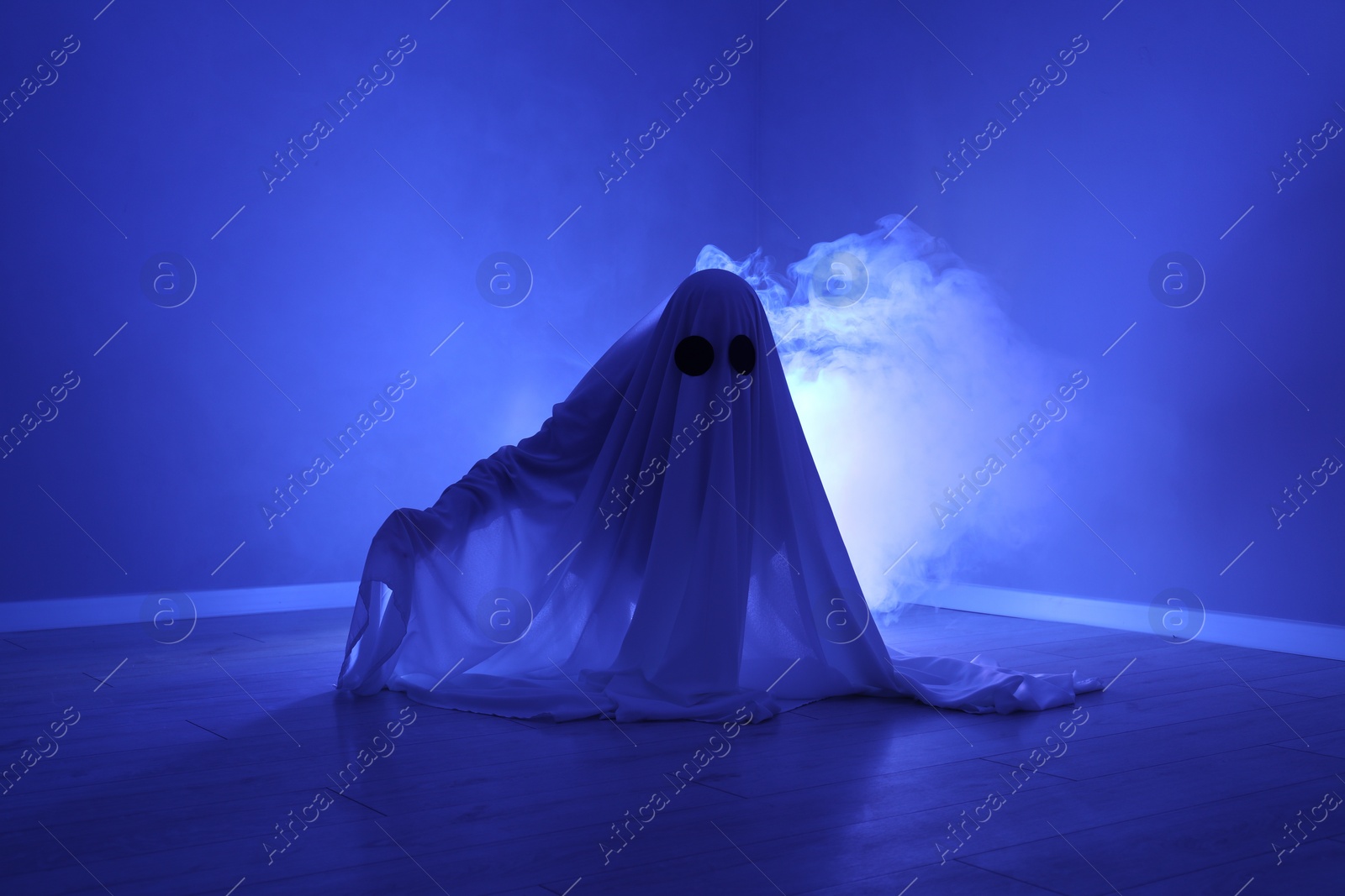 Photo of Creepy ghost. Woman covered with sheet in blue light