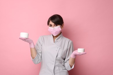 Photo of Cosmetologist with cosmetic products on pink background