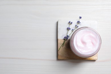 Jar of hand cream and lavender flowers on white wooden table, top view. Space for text