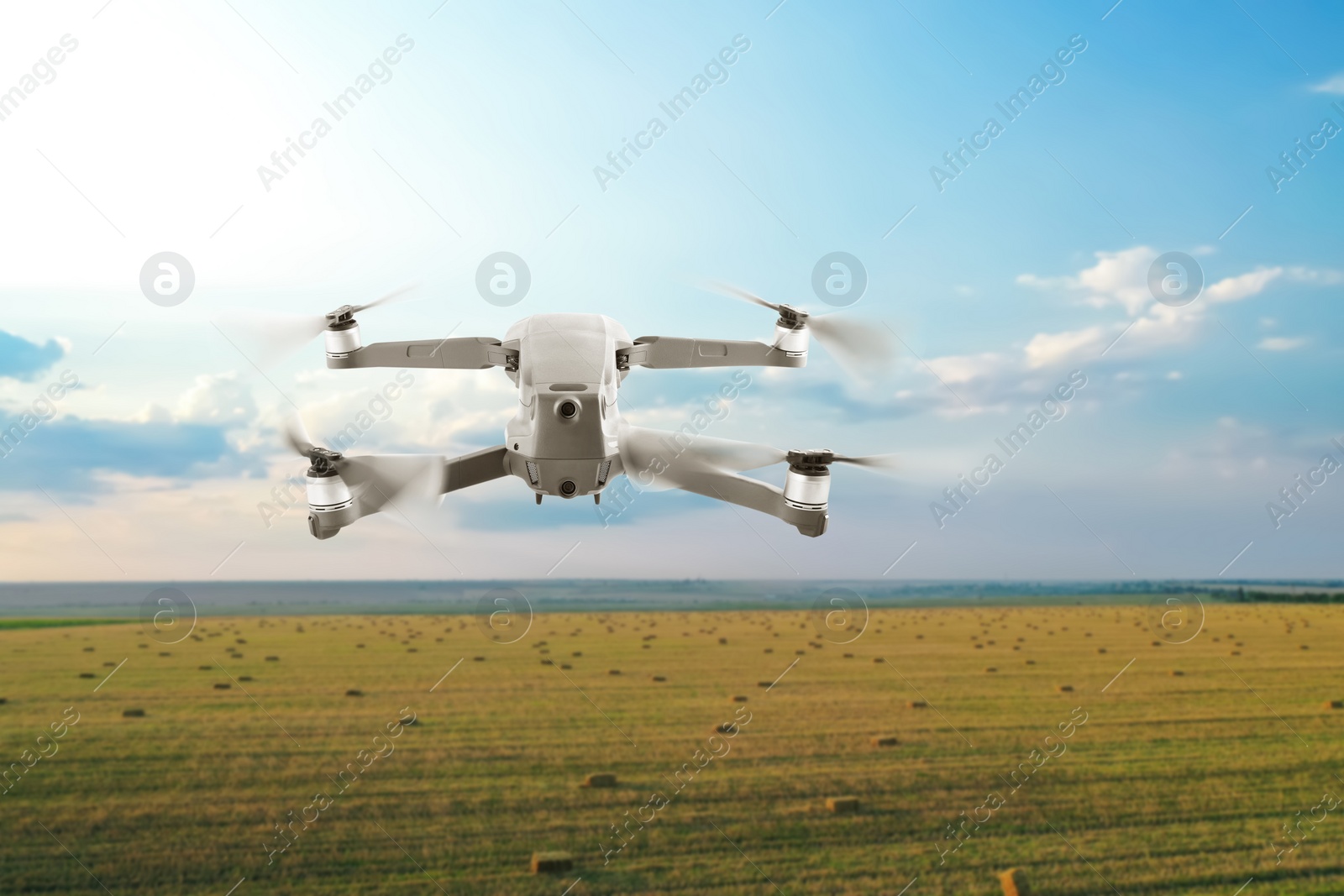 Image of Modern drone flying over field on sunny day. Aerial survey