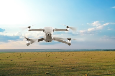Image of Modern drone flying over field on sunny day. Aerial survey