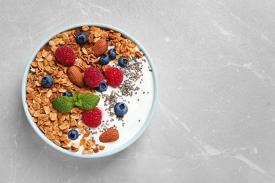 Healthy homemade granola with yogurt and berries on light grey table, top view. Space for text