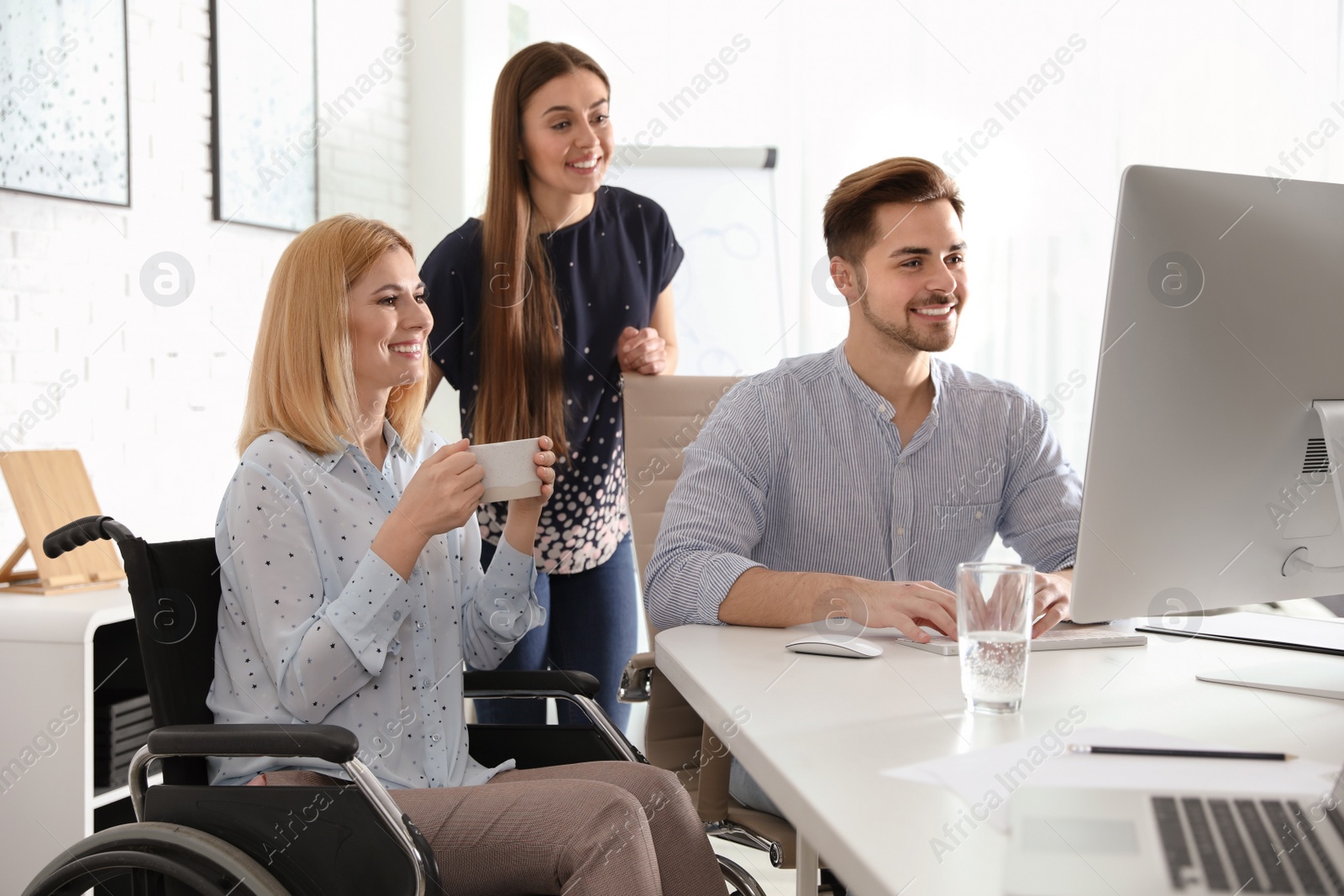 Photo of Portrait of woman in wheelchair with her colleagues at workplace