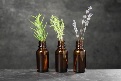 Photo of Bottles with essential oils and plants on grey textured table