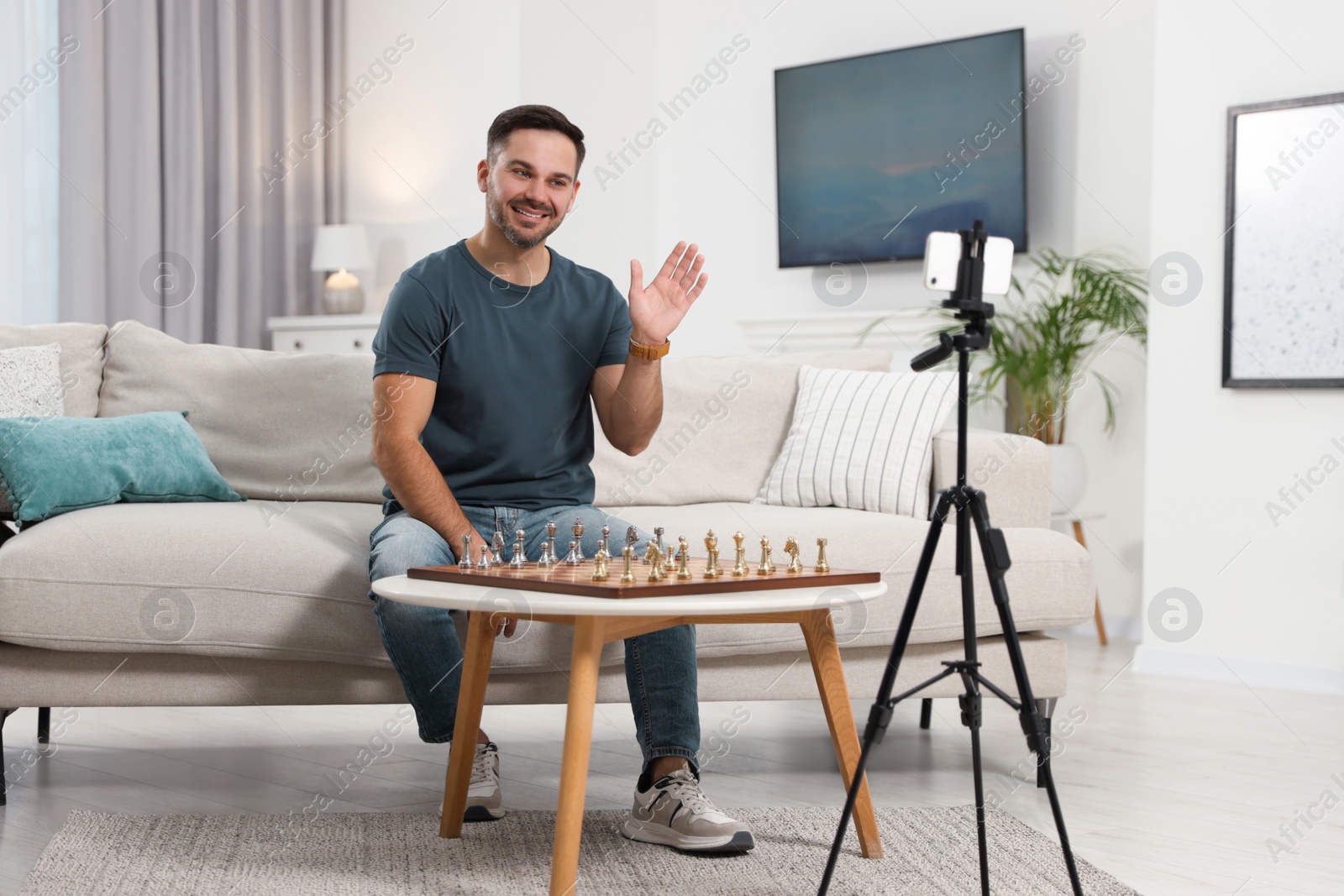 Photo of Teacher near chessboard conducting online lesson at home. Time for hobby