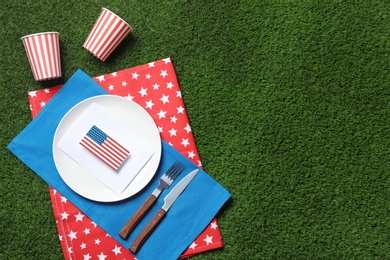 Photo of Set of dishware on green grass, top view with space for text. USA Independence Day