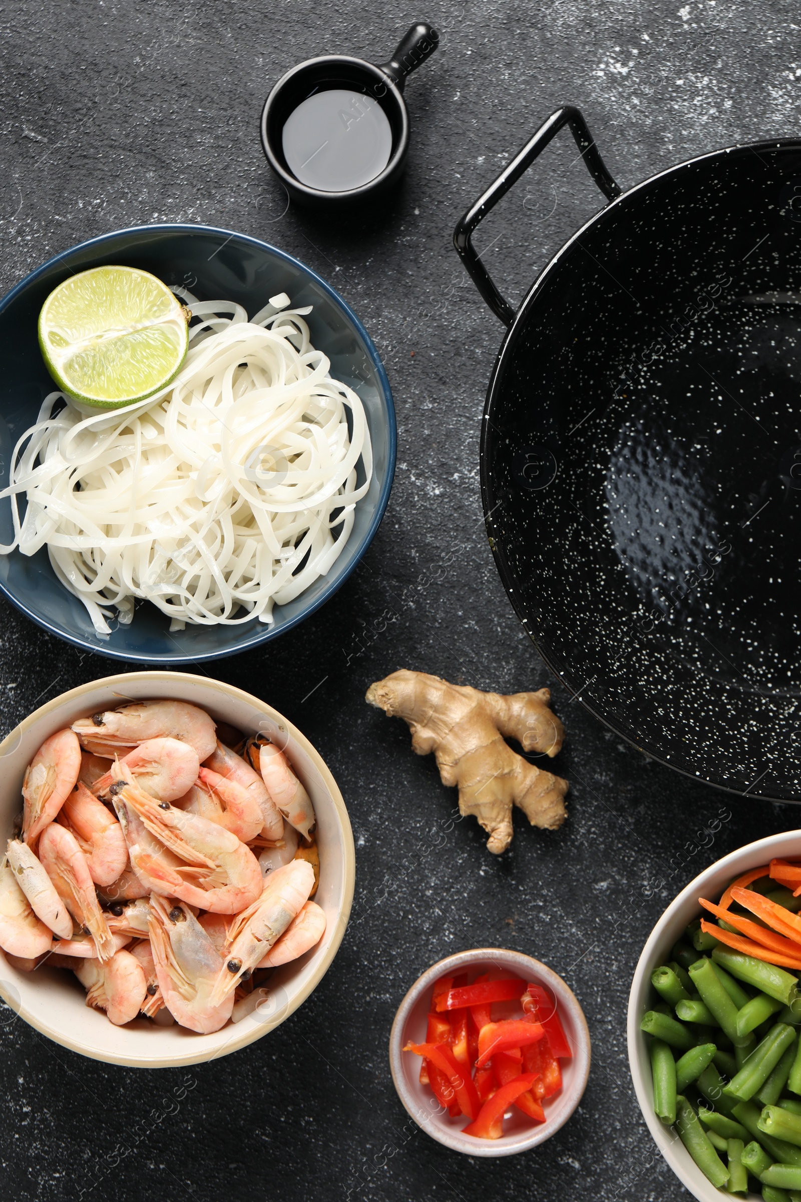 Photo of Flat lay composition with black wok and products on dark textured table