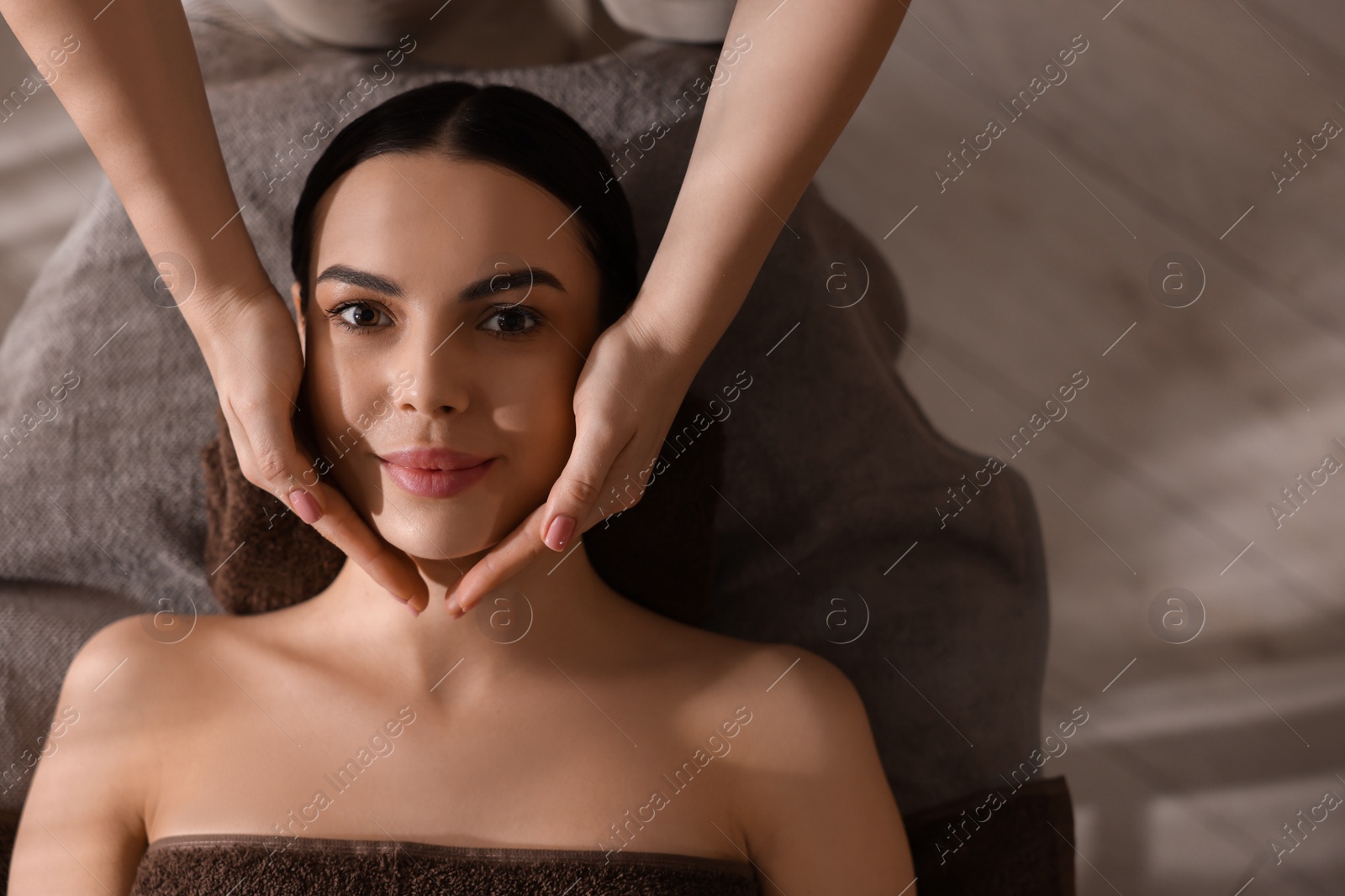 Photo of Spa therapy. Beautiful young woman lying on table during massage in salon, top view. Space for text