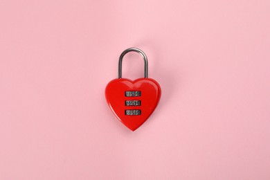 Photo of Red heart shaped combination lock on pink background, top view