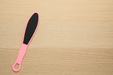 Pink foot file on wooden table, top view with space for text. Pedicure tool