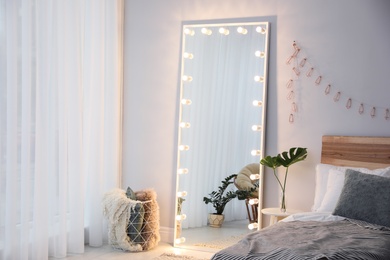 Image of Full length dressing mirror with lamps in stylish bedroom interior