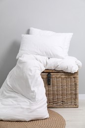 Photo of Soft pillows, duvet and wicker trunk indoors