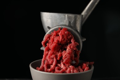 Metal meat grinder with beef mince on black background, closeup